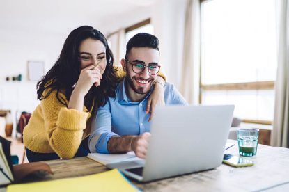Happy Couple Looking at their computer during the day time