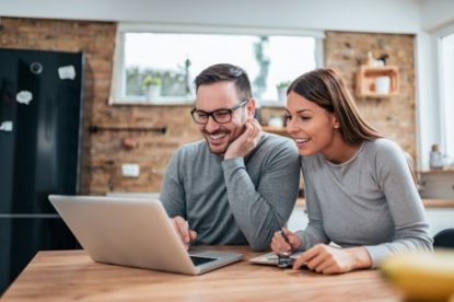 A couple smiling at a laptop